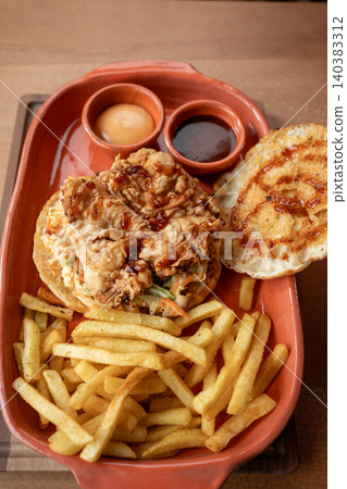Delicious fried chicken sandwich with golden fries served in a rustic setting Delicious fried chicken sandwich with golden fries served in a rustic setting 140383312