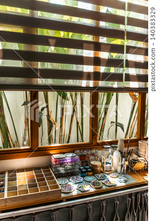 Cozy creative workspace with mosaic art supplies on table by sunlit window, Morning light studio interior with handmade mosaic materials tools and calm atmosphere Cozy creative workspace with mosaic art supplies on table by sunlit window, Morning light studio interior with handmade mosaic materials tools and calm atmosphere 140383329