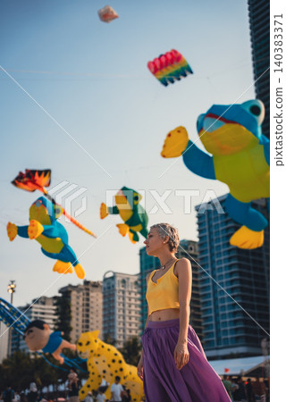 young woman walking on sand beach at colorful kite toys festival during summer sunset, girl enjoying freedom and joy at outdoor event by sea young woman walking on sand beach at colorful kite toys festival during summer sunset, girl enjoying freedom and joy at outdoor event by sea 140383371