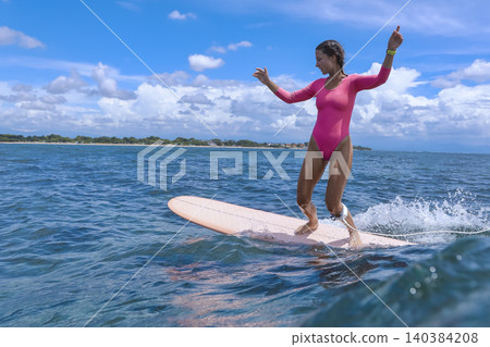 Cheerful Young Lady Balances On surfboard Amid Stormy Skies And Powerful Seas Cheerful Young Lady Balances On surfboard Amid Stormy Skies And Powerful Seas 140384208
