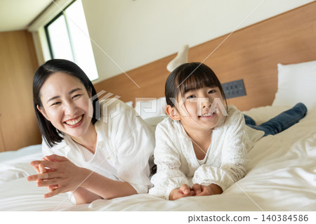 A parent and child lying on a bed 140384586