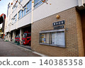 A Japanese fire station characterized by its brick-style walls and rows of red fire trucks in the garage. 140385358
