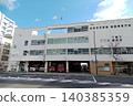 An exterior view of a fire station with ambulances and fire trucks lined up, ready to respond to an emergency. 140385359