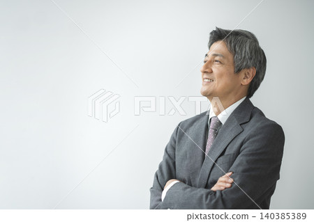 A smiling senior businessman with his arms crossed, profile view. A smiling senior businessman with his arms crossed, profile view. 140385389