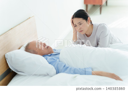 Woman suffering from caregiver burnout while nursing her sick father Woman suffering from caregiver burnout while nursing her sick father 140385860