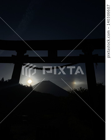 從神社鳥居下方眺望富士山，晨曦和幻日照耀著山的兩側。 140386687