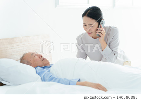 一位臥床不起的老人;一位正在打電話的女士。 一位臥床不起的老人;一位正在打電話的女士。 140386883