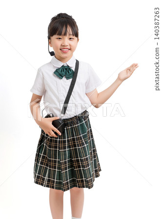 Asian schoolgirl presenting and pointing aside with headset microphone isolated on white background, child host and education concept 140387263
