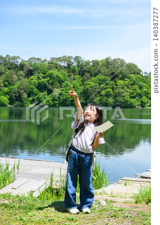 一群小學生在湖邊郊遊,她們興高采烈地舉起手,手裡拿著書籤,周圍是綠樹成蔭的湖面。 一群小學生在湖邊郊遊,她們興高采烈地舉起手,手裡拿著書籤,周圍是綠樹成蔭的湖面。 140387277