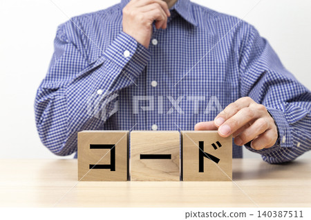 一塊寫著「代碼」字樣的磚塊和一個男人 一塊寫著「代碼」字樣的磚塊和一個男人 140387511