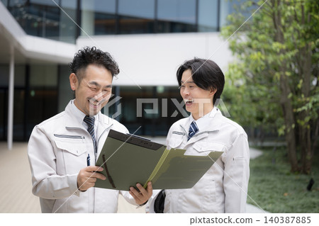 A team of workers conversing on site with a building in the background, related to human resource development in the construction industry, as well as renovations and remodeling. 140387885