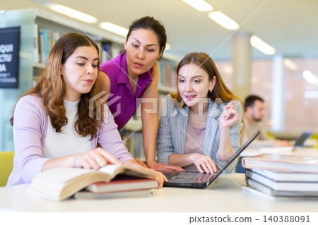 Three female friends studying together at library Three female friends studying together at library 140388091