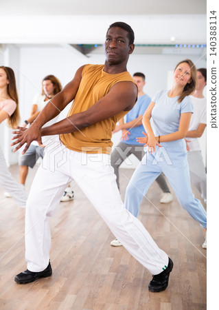 Happy multiracial men women of different ages performing dynamic energetic dancing movements in modern loft studio 140388114