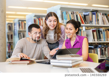 Group of students in the library is preparing for classes on a laptop Group of students in the library is preparing for classes on a laptop 140388269