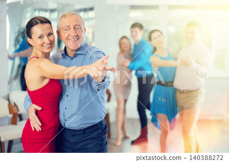 Happy people of different ages dancing tango in pairs in dance hall Happy people of different ages dancing tango in pairs in dance hall 140388272