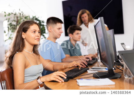 Girl student of computer courses looks at monitor screen, types on keyboard and does work Girl student of computer courses looks at monitor screen, types on keyboard and does work 140388364