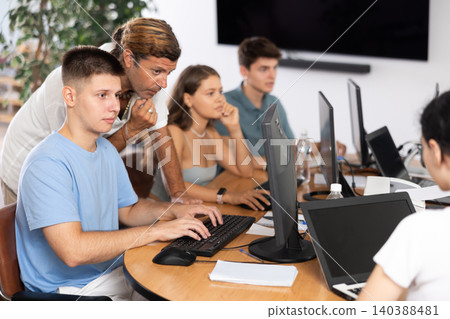Interested guy attending computer class under guidance of male teacher Interested guy attending computer class under guidance of male teacher 140388481