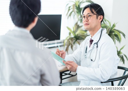 一位身穿白大褂的醫生微笑著與病人交談。身體檢查、診所、健康管理、壓力測試。 一位身穿白大褂的醫生微笑著與病人交談。身體檢查、診所、健康管理、壓力測試。 140389063