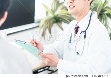 一位身穿白大褂的醫生微笑著與病人交談。體檢。診所。沒有面孔。 一位身穿白大褂的醫生微笑著與病人交談。體檢。診所。沒有面孔。 140389064