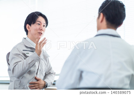 一名身穿工作服的男子正在接受職業醫生的體檢;健康檢查;腹痛;頭痛;諮詢。 一名身穿工作服的男子正在接受職業醫生的體檢;健康檢查;腹痛;頭痛;諮詢。 140389075
