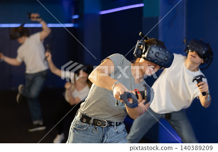 Excited young woman in VR goggles having fun in virtual reality room Excited young woman in VR goggles having fun in virtual reality room 140389209