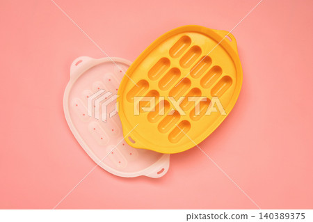 Yellow and White Silicone Sausage Molds on Pink Background Yellow and White Silicone Sausage Molds on Pink Background 140389375
