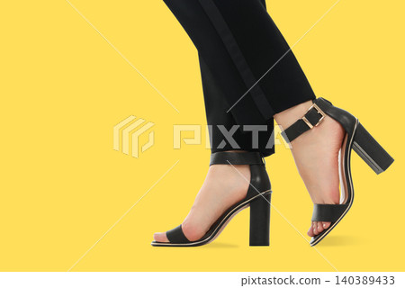 A woman wears black high heel sandals with a simple design A woman wears black high heel sandals with a simple design 140389433