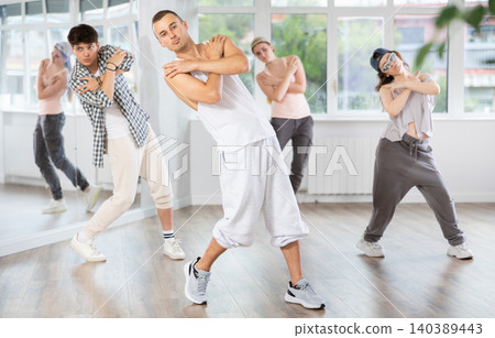 Young guy practicing basic hip hop moves in training hall Young guy practicing basic hip hop moves in training hall 140389443