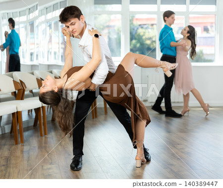 Guy and girl in couple spins to rhythm of tango during lesson for novice students. Classes in mini groups for those who want to learn dancing 140389447