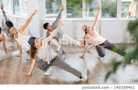 Girl and her students perform hip hop dance on one bent leg, movement in horizontal plane near floor Girl and her students perform hip hop dance on one bent leg, movement in horizontal plane near floor 140389461