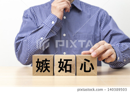 A block with the word "jealousy" written on it and a man A block with the word "jealousy" written on it and a man 140389503