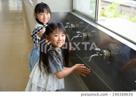 小學生在學校的飲水機前快樂地洗手。 小學生在學校的飲水機前快樂地洗手。 140389639