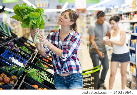 Woman choosing lettuce in supermarket Woman choosing lettuce in supermarket 140389643