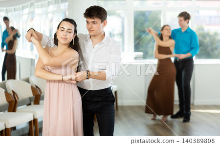 Hispanic guy practicing bachata with young brunette in dance class Hispanic guy practicing bachata with young brunette in dance class 140389808