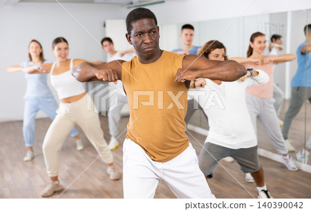 Big group of young adult fit people in activewear exercising together during training in dance studio 140390042
