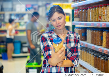 Woman selecting pickled products in grocery store Woman selecting pickled products in grocery store 140390050