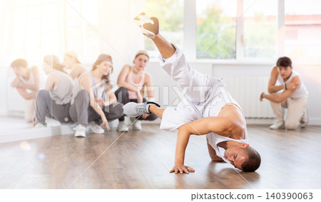 Young guy breakdancing in front of group members watching him Young guy breakdancing in front of group members watching him 140390063