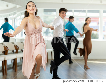 Couple in evening dresses enjoys pair dance boogie-woogie, interacting with each other on floor Couple in evening dresses enjoys pair dance boogie-woogie, interacting with each other on floor 140390112