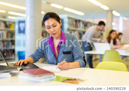 Asian student woman in the library studying on a laptop Asian student woman in the library studying on a laptop 140390226