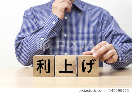 A block with the words "Interest Rate Hike" written on it and a man 140390923