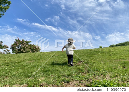 Toddlers climbing a grassy hill under a blue sky Toddlers climbing a grassy hill under a blue sky 140390970