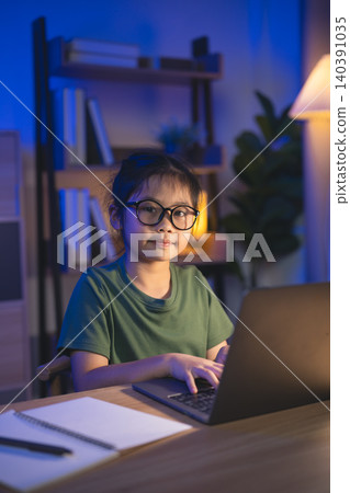 Child Girl Wearing Glasses Sitting at Desk with Laptop in Cozy Home Office During Evening Studying or Working with Books and Notebook Child Girl Wearing Glasses Sitting at Desk with Laptop in Cozy Home Office During Evening Studying or Working with Books and Notebook 140391035