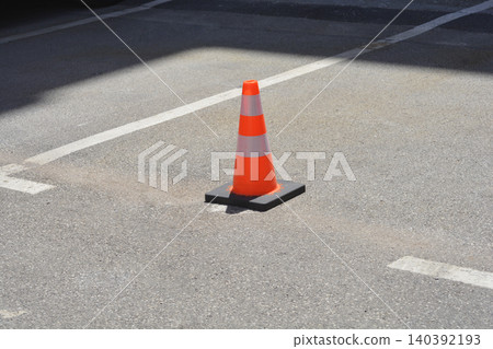 Orange traffic cone with reflective stripes on an asphalt parking space Orange traffic cone with reflective stripes on an asphalt parking space 140392193