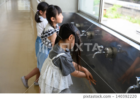 小學生們正在學校的飲水機前認真洗手。 小學生們正在學校的飲水機前認真洗手。 140392220