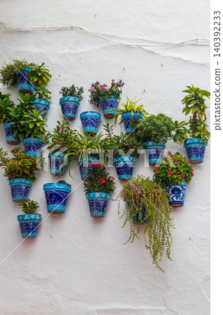 Traditional Andalusian Blue Ceramic Flower Pots with Beautiful Flowers and Plants Hanging on a Whitewashed Wall in Andalusia, Spain 140392233