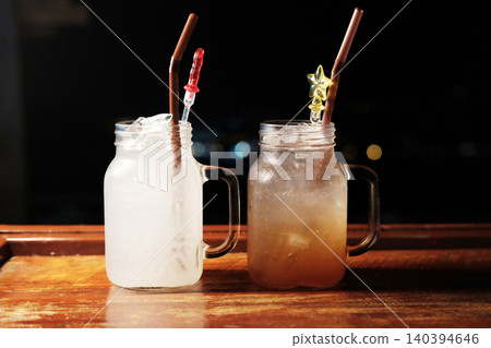 Fresh two glasses of ice Lemonade juice and plum juice on wooden counter in the night Fresh two glasses of ice Lemonade juice and plum juice on wooden counter in the night 140394646