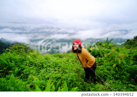 Tourist Asian young woman smiling happy and wearing red hat and yellow jacket standing on peak of mountains and mist in the morning of Thailand Tourist Asian young woman smiling happy and wearing red hat and yellow jacket standing on peak of mountains and mist in the morning of Thailand 140394652