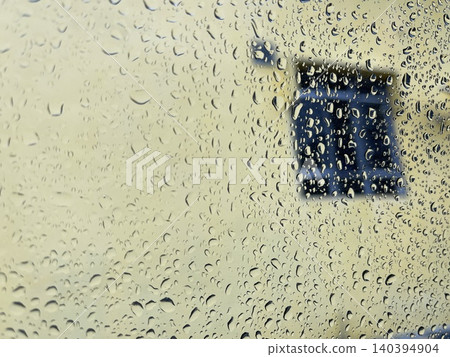 Raindrops on Window Glass with Blurred Yellow Wall and Blue Window Background Raindrops on Window Glass with Blurred Yellow Wall and Blue Window Background 140394904