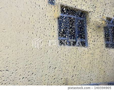 Raindrops on Window Glass with Blurred Yellow Wall and Blue Window Background Raindrops on Window Glass with Blurred Yellow Wall and Blue Window Background 140394905