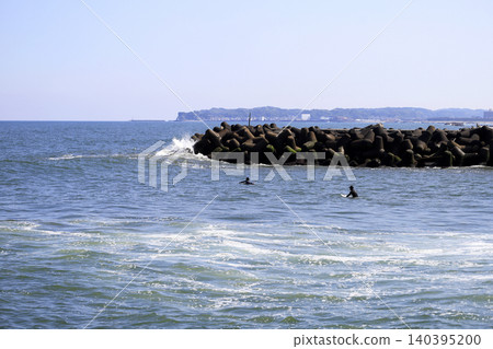 People enjoying surfing near the river mouth along the coastline People enjoying surfing near the river mouth along the coastline 140395200